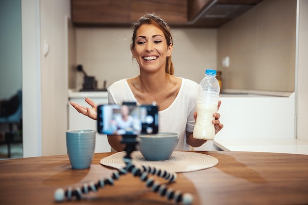 Beautiful young woman is filming her blog broadcast about healthy food at home.