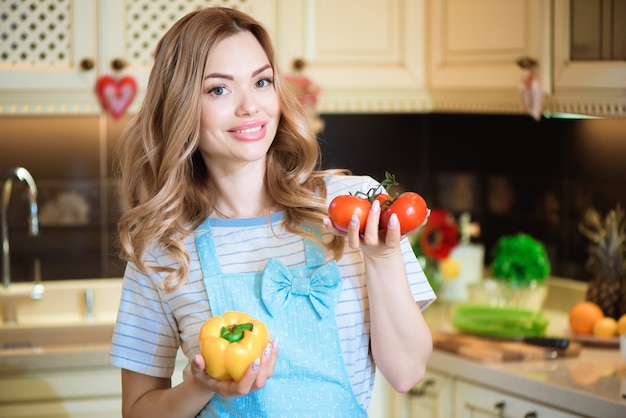 Beautiful young woman is preparing vegetable salad in the kitchen. Healthy Food.  