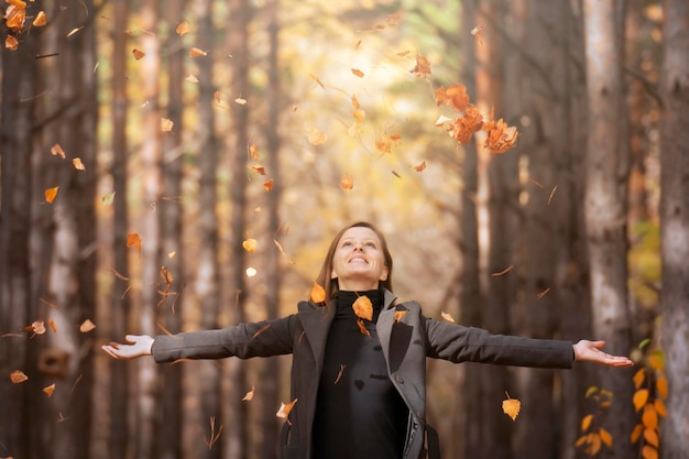 A beautiful young woman is resting in the park in the autumn season with her eyes closed The breath of autumn and the change of seasons falling leaves from trees fresh air and freedom