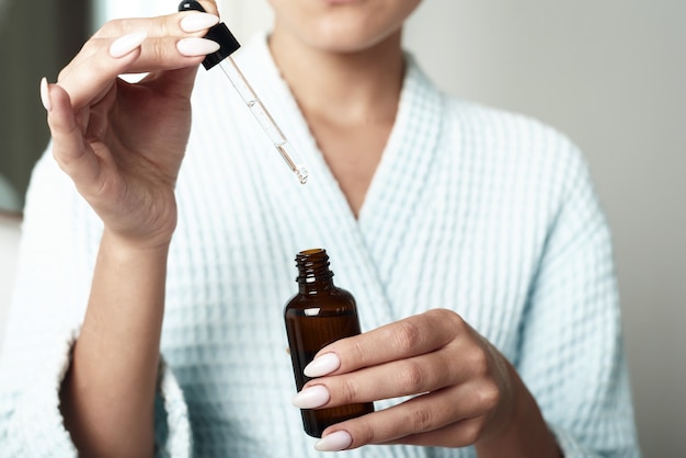 Beautiful Young Woman is Using Moisturizer Anti-Aging Serum Treatment on Her Hands. Beauty Body Skin Care and Cosmetic Apply Concept.