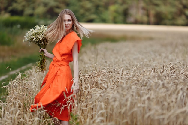 A beautiful young woman is walking in a wheat field