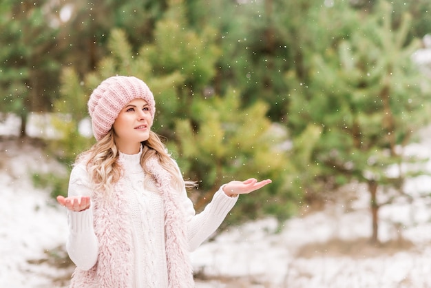 Beautiful young woman in jeans and pink jacket in winter forest