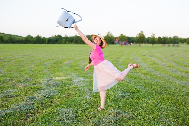 Photo beautiful young woman laughs and dances outdoors in a meadow during sunset