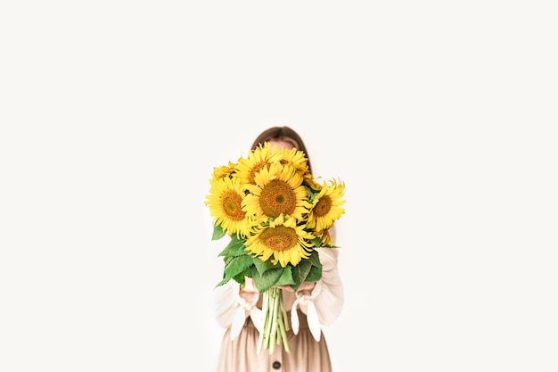 Beautiful young woman in linen dress holding sunflowers bouquet on white