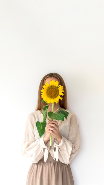 Beautiful young woman in linen dress holding sunflowers bouquet on white