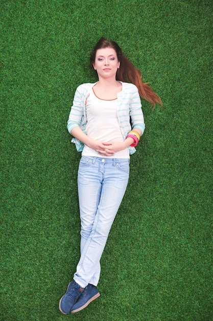 Beautiful young woman lying on the green grass