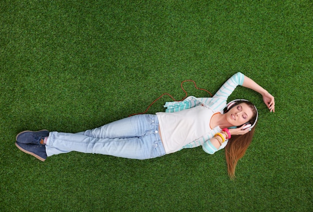 Beautiful young woman lying on the green grass