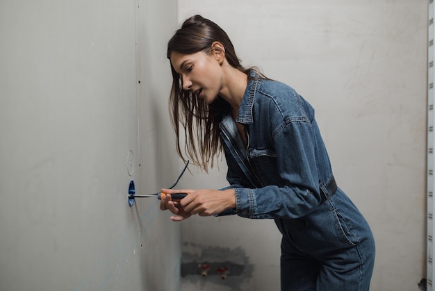 A beautiful young woman makes repairs at home high quality photo