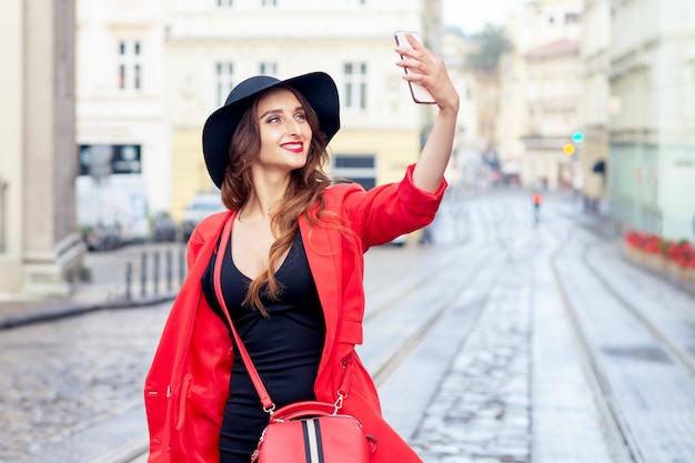 Beautiful young woman makes selfie in the city.