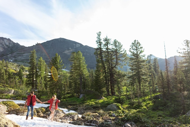 Beautiful young woman and man walk hug and kiss in mountain nature at sunse