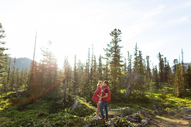 Beautiful young woman and man walk hug and kiss in mountain nature at sunse