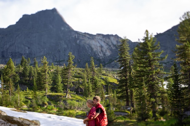 Beautiful young woman and man walk hug and kiss in mountain nature with tiltshift effect