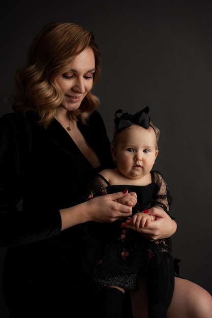 Beautiful young woman mother of little baby on dark background