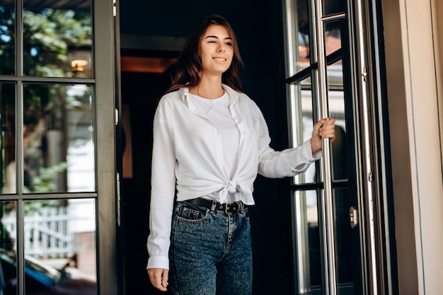 Beautiful young woman opening a glass doors to get out