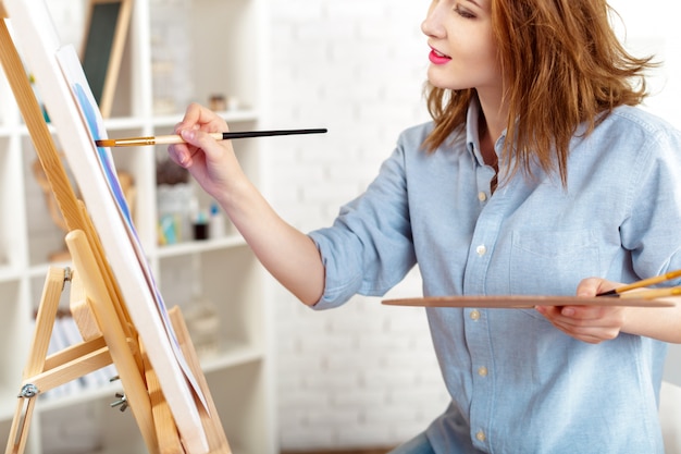 Beautiful young woman painter at work