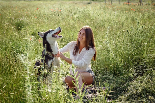 Beautiful young woman playing with funny husky dog outdoors at park