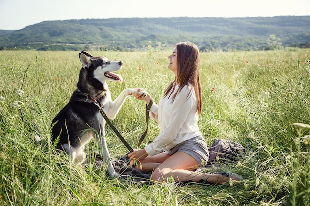 Beautiful young woman playing with funny husky dog outdoors at park