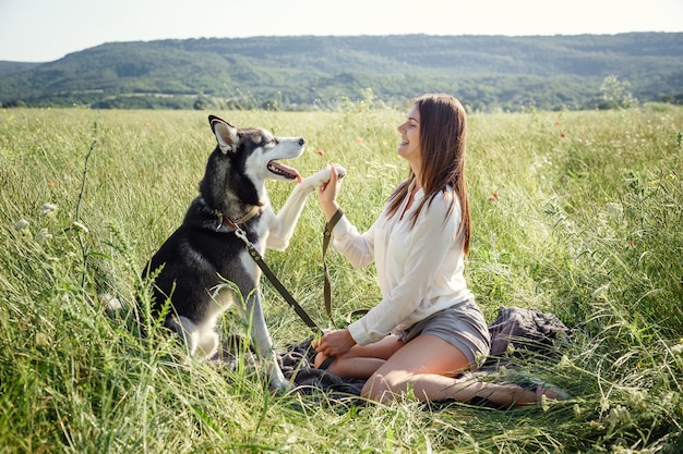 Beautiful young woman playing with funny husky dog outdoors at park