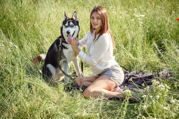 Beautiful young woman playing with funny husky dog outdoors at park