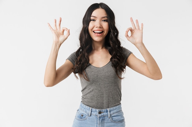 a beautiful young woman posing isolated over white wall showing okay gesture.