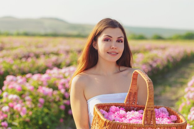 Beautiful young woman posing near roses in a garden.