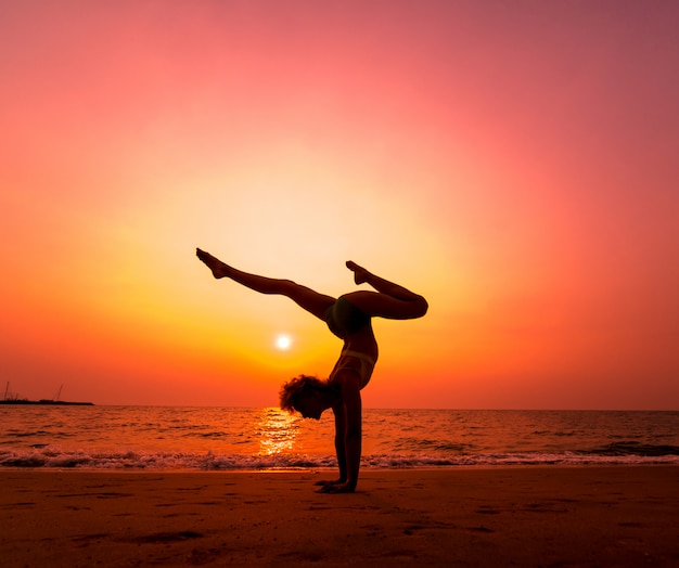 Photo beautiful young woman practic yoga at the beach. early morning exercise. sunrise