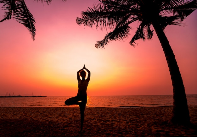 Beautiful young woman practic yoga at the beach. Early morning exercise. Sunrise