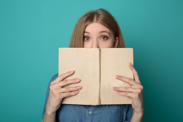 beautiful young woman reading book on blue background