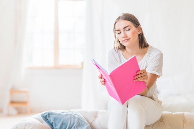 Beautiful young woman reading book at home