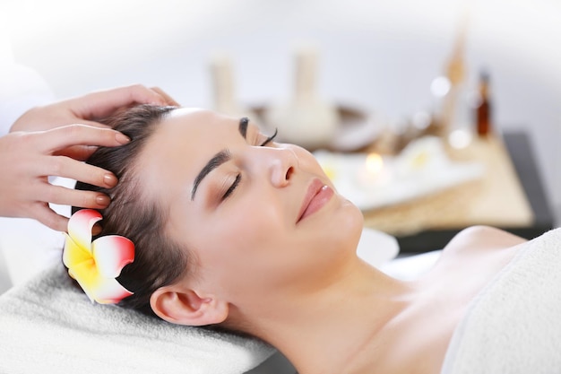 Beautiful young woman relaxing with face massage at beauty spa