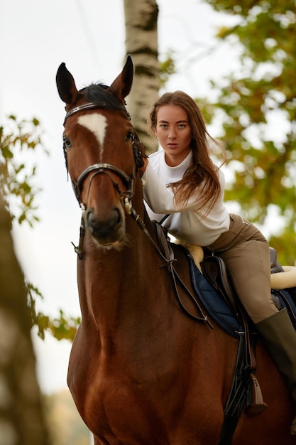 Beautiful young woman riding a horse on the field Sideways to the camera Freedom joy movement