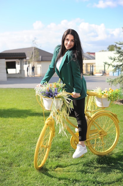 Beautiful young woman riding a yellow bike