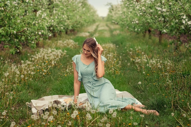 Beautiful young woman in a romantic dress on a picnic in spring in a blooming garden