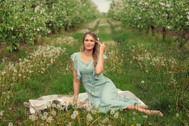 Beautiful young woman in a romantic dress on a picnic in spring in a blooming garden