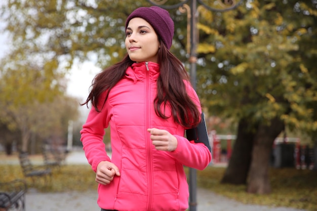 Beautiful young woman running in autumn park