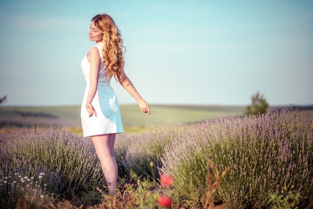 Beautiful young woman in a rural field full of lavender flowers