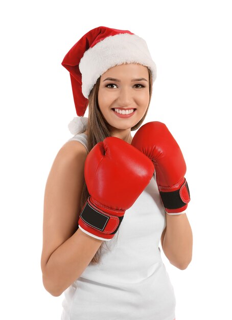 Beautiful young woman in Santa Claus hat and boxing gloves on white background. Boxing Day concept