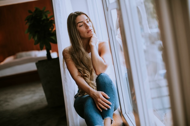 Beautiful young woman sitting by the window