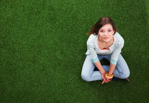 Beautiful young woman sitting on the green grass