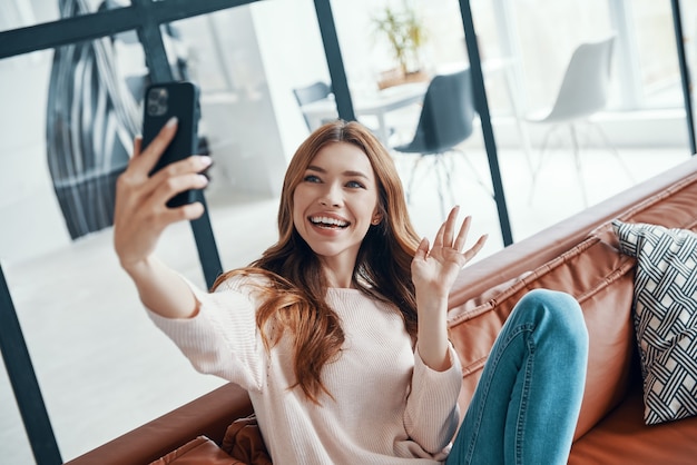 Photo beautiful young woman sitting on the sofa at home