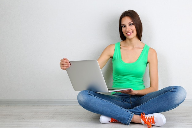 Beautiful young woman sitting with laptop in room