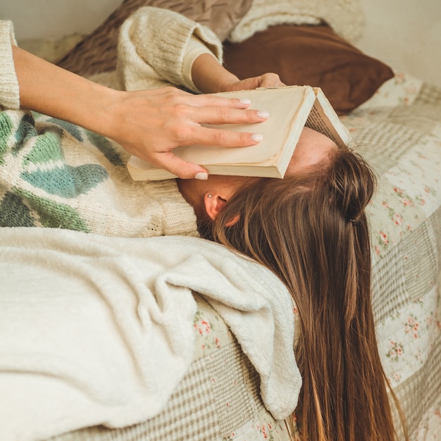 Beautiful young woman sleeping on bed with book covering her face because reading book with preparing exam of college, woman sleepy with tired so that leisure, relax and education concept.