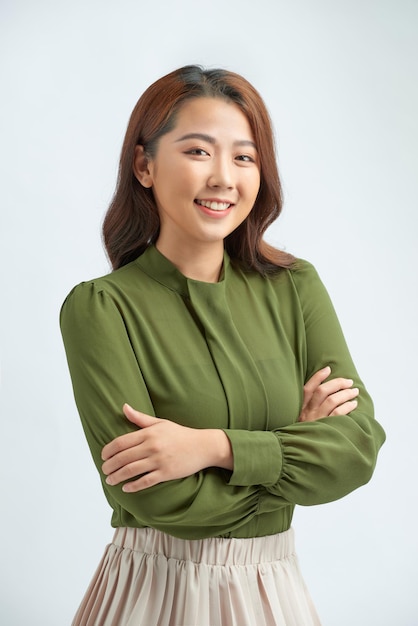 Beautiful young woman in smart casual wear keeping arms crossed and smiling while standing against grey background