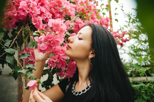 Beautiful young woman smelling spring flowers Beautiful bougainvillea flowers in the hand of a girl with dark flowing hair