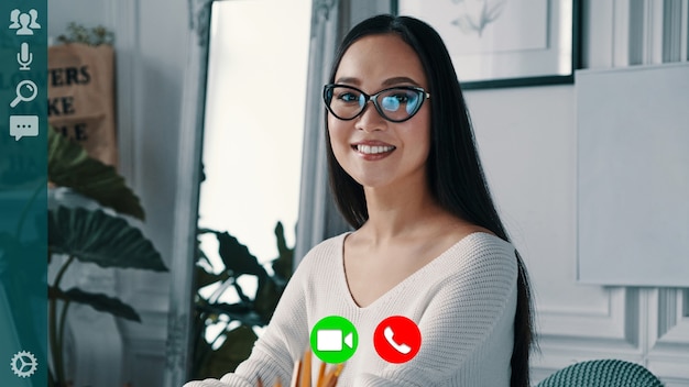 Beautiful young woman smiling and looking at camera while having video call