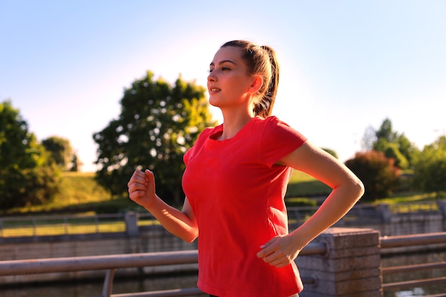 Beautiful young woman in sports clothing running while exercising outdoors.