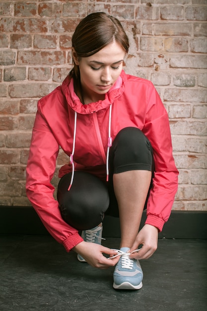 Beautiful young woman in sportswear tie shoelaces