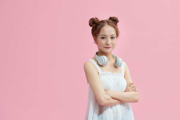 Beautiful young woman standing with arms crossed over a pink background