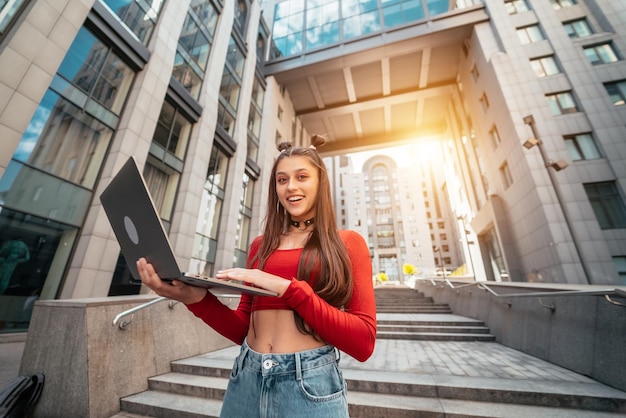 Beautiful young woman on the street using laptop