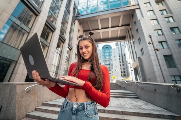 Beautiful young woman on the street using laptop